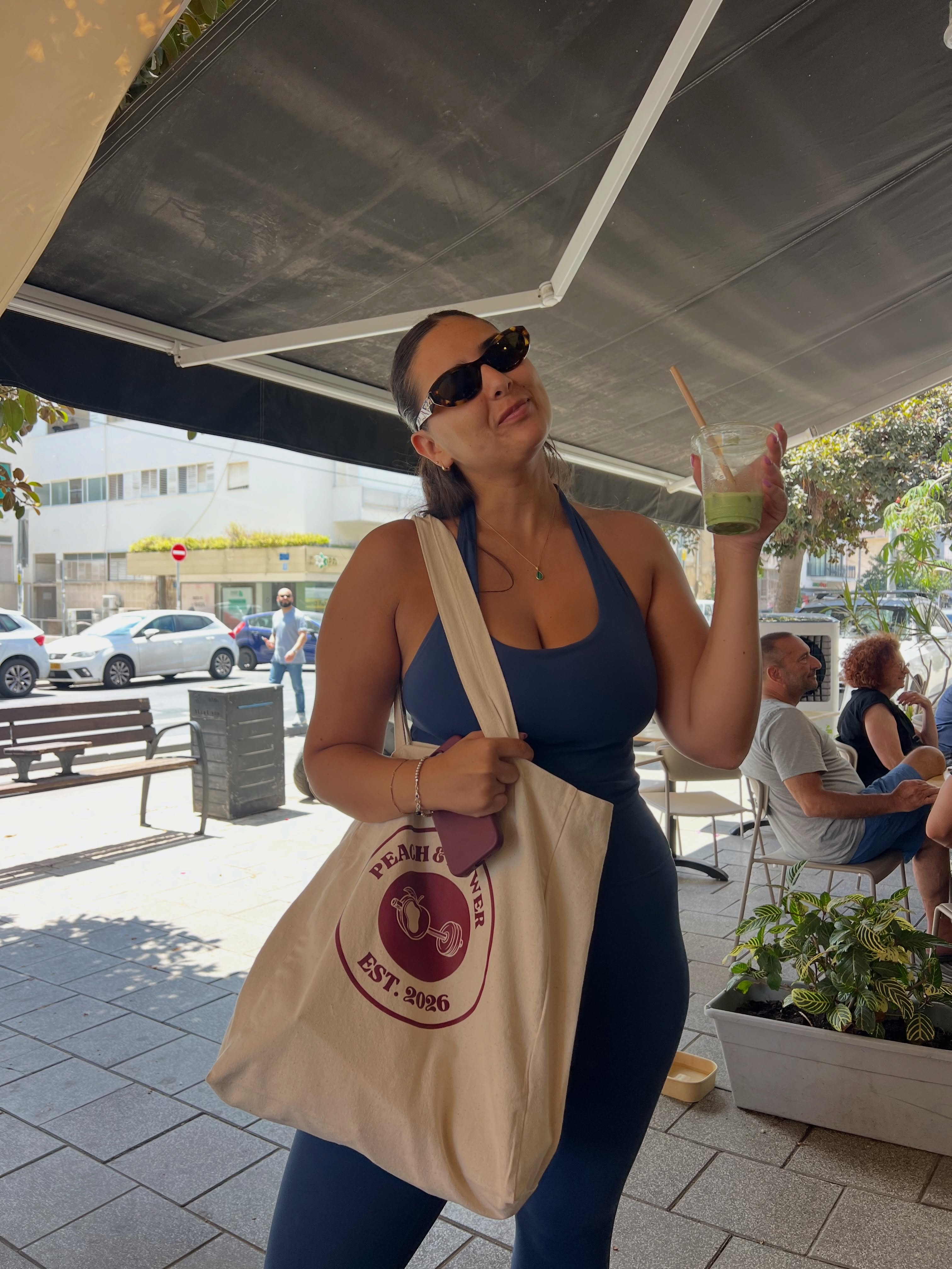 Studio member with an iced drink holding a branded tote bag outside