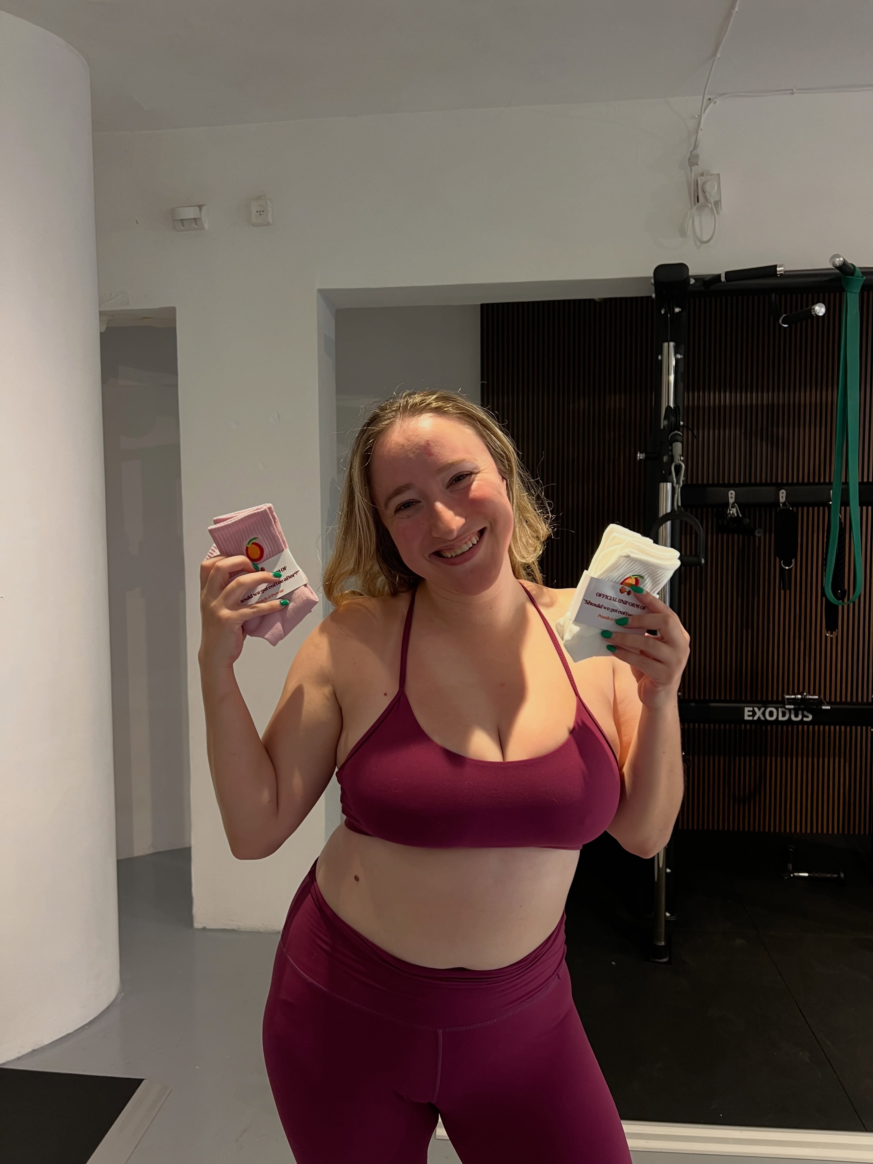 Smiling member holding branded socks inside the gym